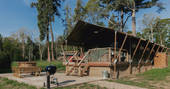 The Cowshed safari tent with hot tub and BBQ outside at The Lost Garden Retreat in Suffolk