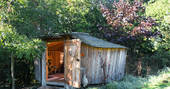 Pixie Yurt nestled in the tree’s with the front door open at Mill Valley in Cornwall