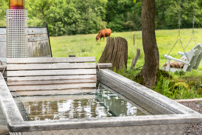 The hot tub with a cow in the field in the background at Dimpsey Yonder Shepherd's Hut in Somerset