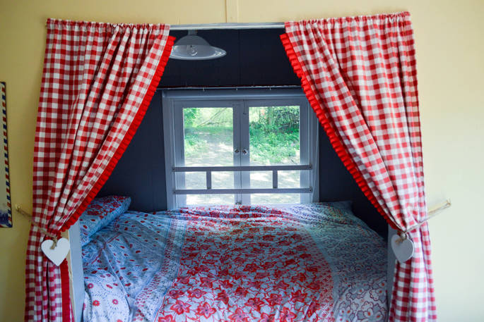 Cosy double bed with chic bedding and window looking out on the forest 